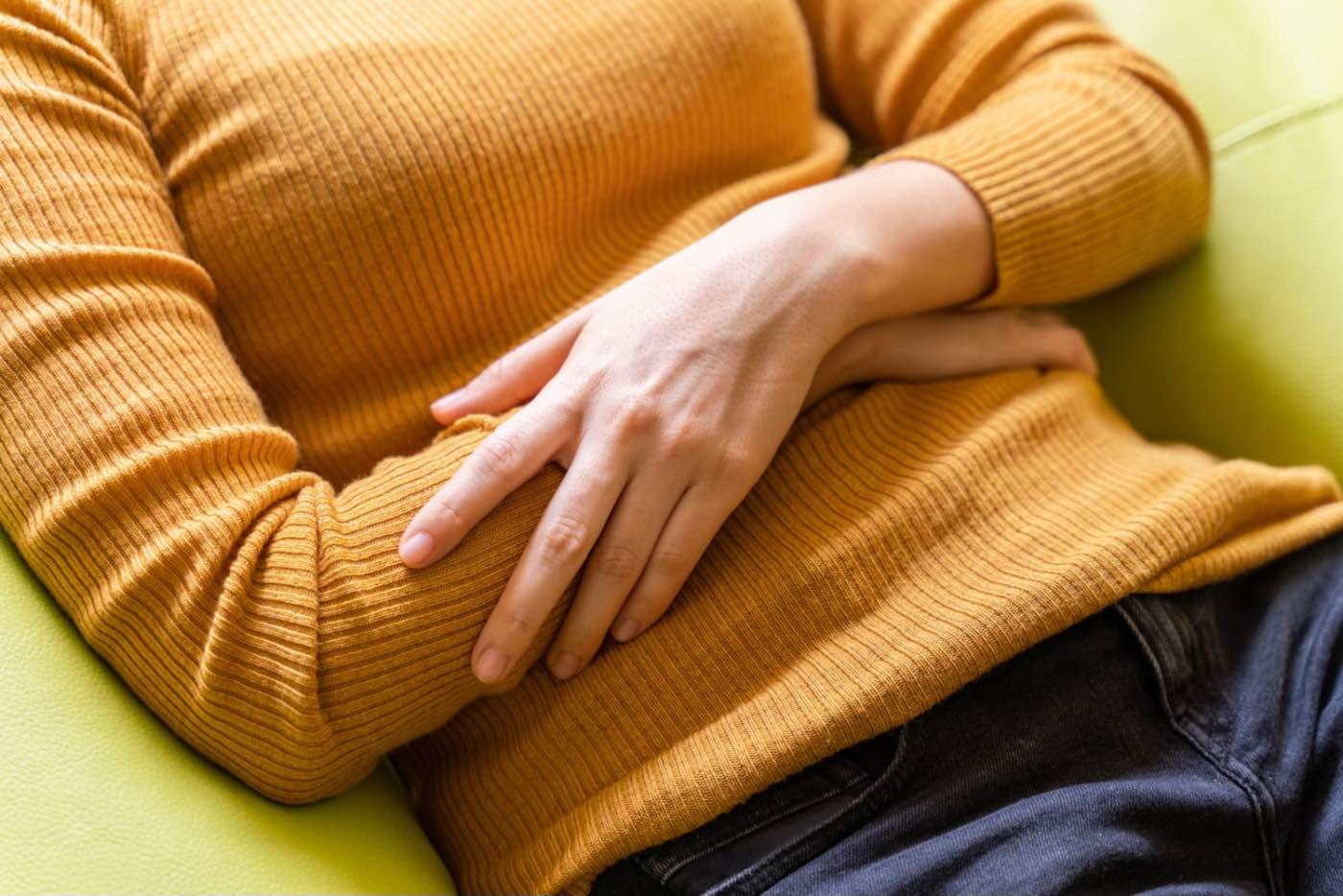 Limbricii la om (femeie care se tine de burta, infectie parazitara, durere, pulover caramiziu)