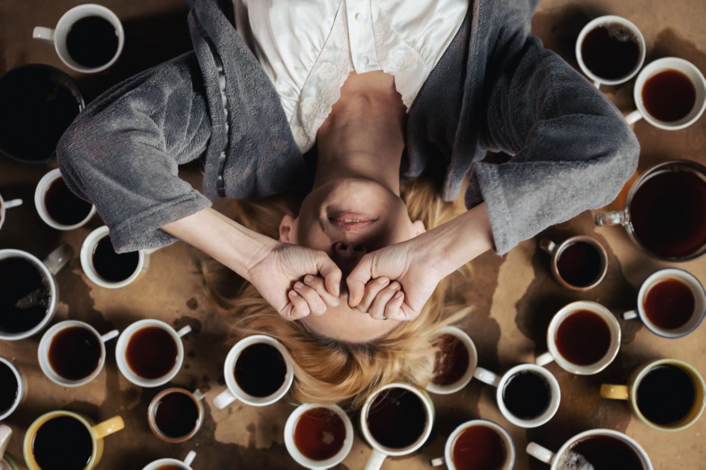 Dependenta de cafea (femeie care isi acopera fata, durere de cap, cani pline cu cafea, problema cu cofeina)