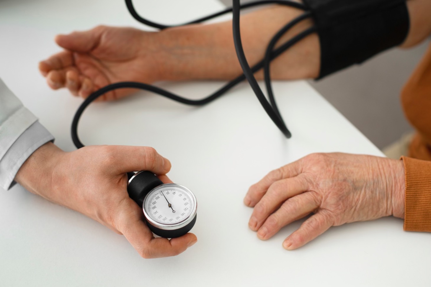 Tensiunea oscilanta la batrani (medic care ia tensiunea unui batran, mana nemiscata, cabinet medical)