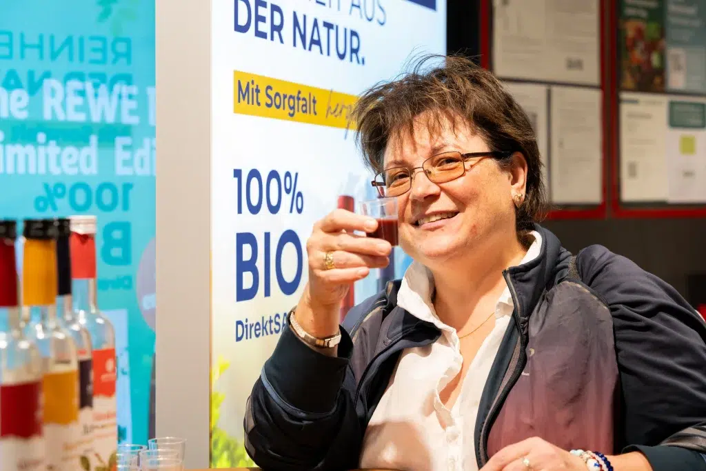 Clientă gustând suc BIO Aronia Charlottenburg la degustarea REWE din München